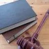 Ein hölzerner Richterhammer neben zwei Gesetzbüchern auf einem Holztisch