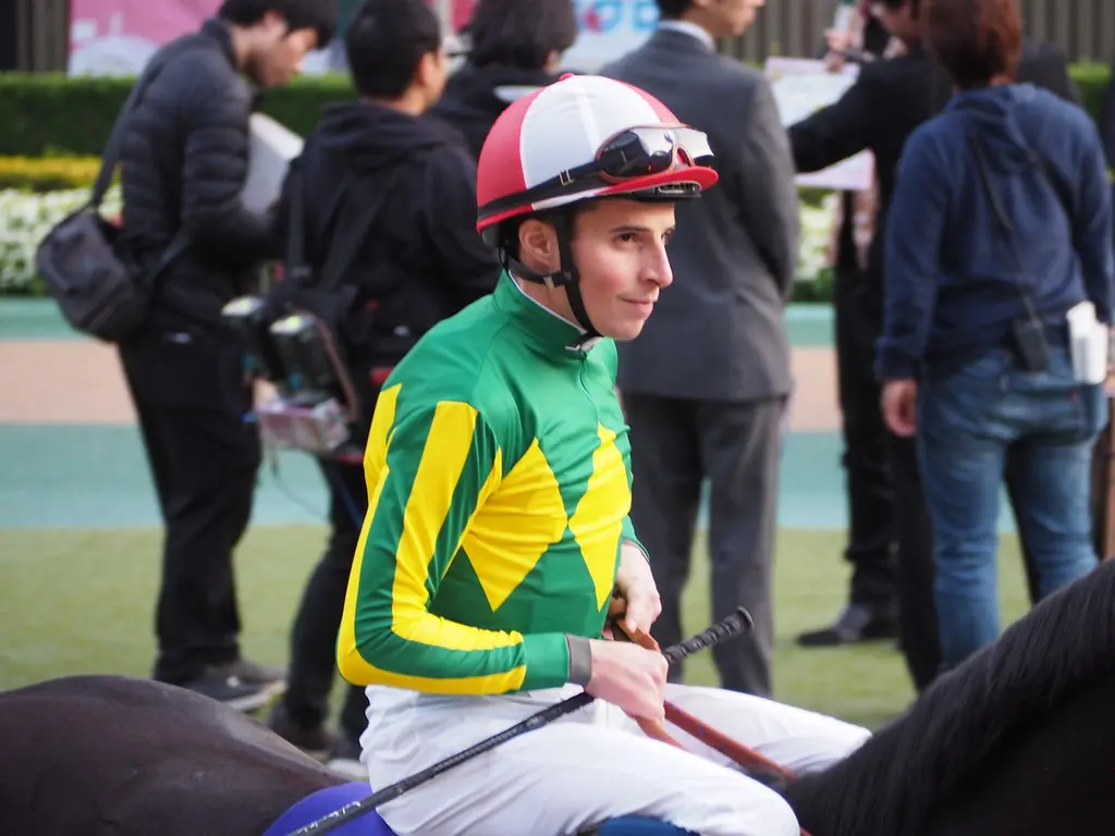 Le jockey William Buick portant une casaque verte et jaune et un casque rouge et blanc.