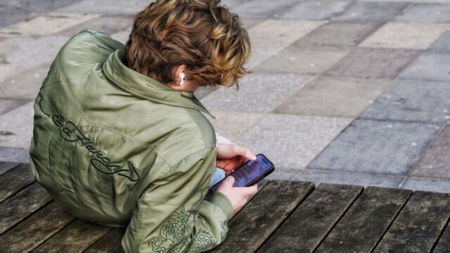 Een man kijk op zijn telefoon naar streams op online platformen zoals Youtube en Twitch