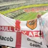 Jacob och hans morfar Geoff håller en Hull City-flagga på läktaren under fotbolls-VM i Mexiko