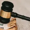 Domarklubba ovanpå sedlar som symboliserar sanktionsavgifter och rättsliga beslut