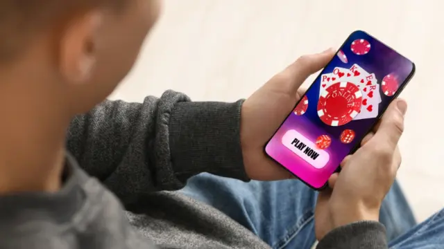 Ung person med nätcasino öppet på mobiltelefonen