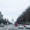 Traffic moves along a Washington, DC street with the US Capitol building visible in the background.