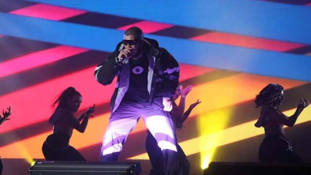 Bad Bunny performing live on stage during a concert with dancers and colorful lighting