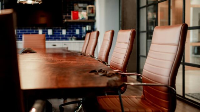 Empty corporate boardroom table with leather chairs