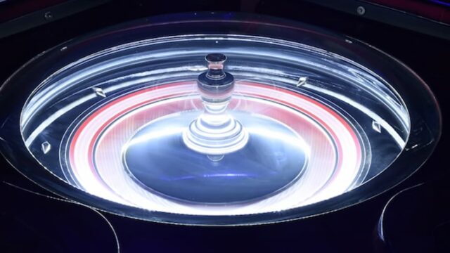 Close-up of a roulette wheel spinning under bright studio lighting in a casino environment
