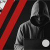 Hooded figure using a laptop next to casino chips, representing online casino scams