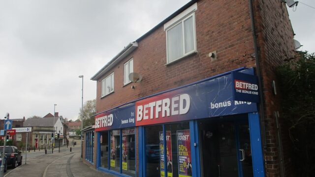 A Betfred betting shop with blue storefront signage and betting advertisements in the windows