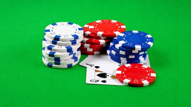Stacks of poker chips and playing cards on a green casino table