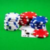 Stacks of poker chips and playing cards on a green casino table