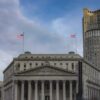 Large courthouse building in New York City with American flags outside under a cloudy sky