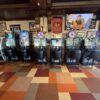 A row of POMI Distribution sweepstakes gaming machines installed inside a Chicago bar, with multiple electronic terminals, chairs and promotional displays visible.