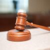 A wooden judge's gavel rests on a courtroom bench.