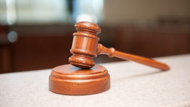A wooden judge's gavel rests on a courtroom bench.