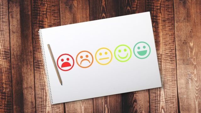 Survey satisfaction icons ranging from negative to positive displayed on a notepad, representing public opinion and poll results.