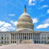 Front view of the United States Capitol building beneath a blue sky with scattered white clouds.