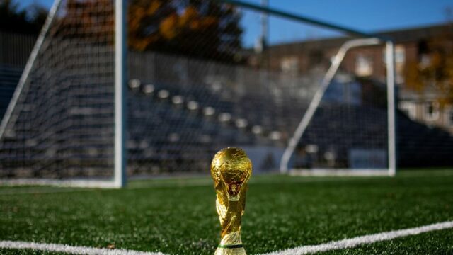 World Cup trophy displayed on a soccer field in front of a goal