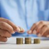 Hands stacking coins to represent commercial and tribal gaming revenue growth despite ongoing debate over prediction markets.