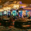 Casino floor with slot machines, gaming tables and chandeliers inside a modern casino.