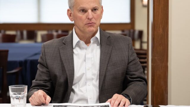 Josh Stein seated at a table wearing a gray blazer and white shirt.