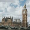 The Palace of Westminster, the Elizabeth Tower (Big Ben), and Westminster Bridge under a cloudy sky in London.