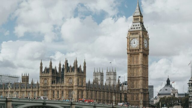 The Palace of Westminster, the Elizabeth Tower (Big Ben), and Westminster Bridge under a cloudy sky in London.