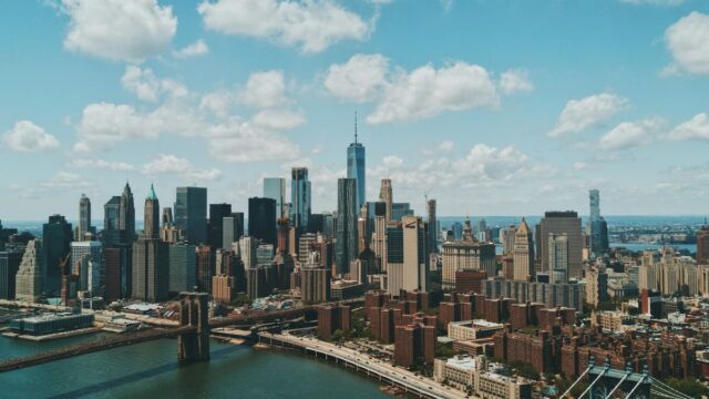Aerial view of the Lower Manhattan skyline in New York City, including One World Trade Center and the Brooklyn Bridge.