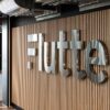 Flutter Entertainment logo mounted on a wooden wall inside a company office.