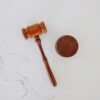 Wooden judge’s gavel and sound block on a white marble surface.