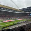 Packed Wembley Stadium with U.K. and U.S. flags displayed across the field before an NFL game.