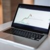 Laptop displaying a financial trading chart on its screen.
