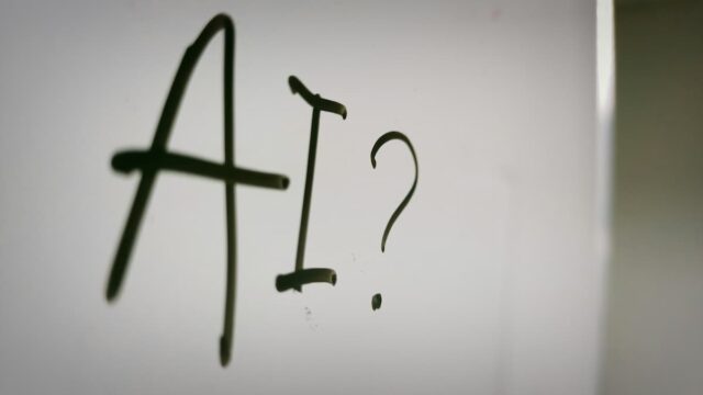 The letters “AI” and a question mark written in black on a white surface. AI Questions Amid DraftKings Scrutiny